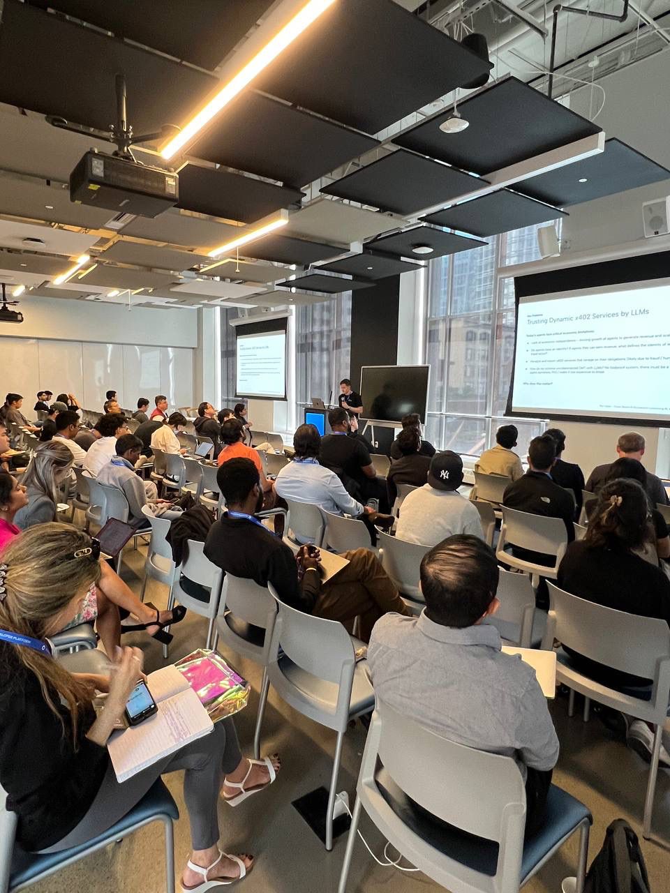 The audience at the AWS Builder Loft during the Infinite Bazaar presentation, with a slide titled 'Trusting Dynamic x402 Services by LLMs'